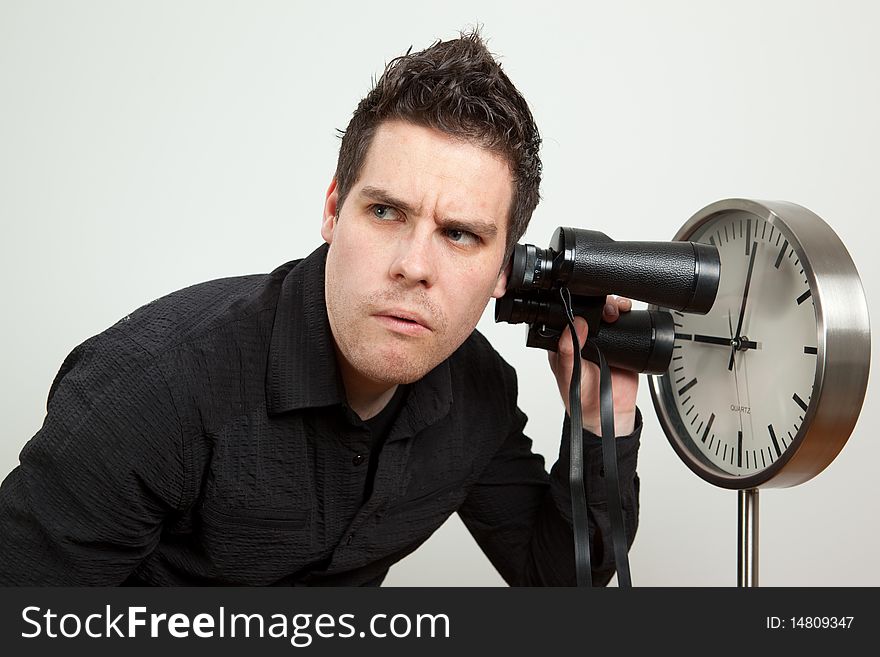 Guy holding binoculars and listening the clock. Guy holding binoculars and listening the clock