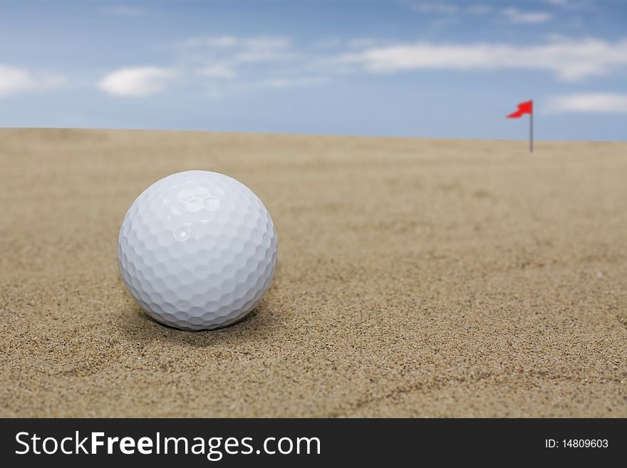 Golf ball on sand field in back the flag that signs the hole