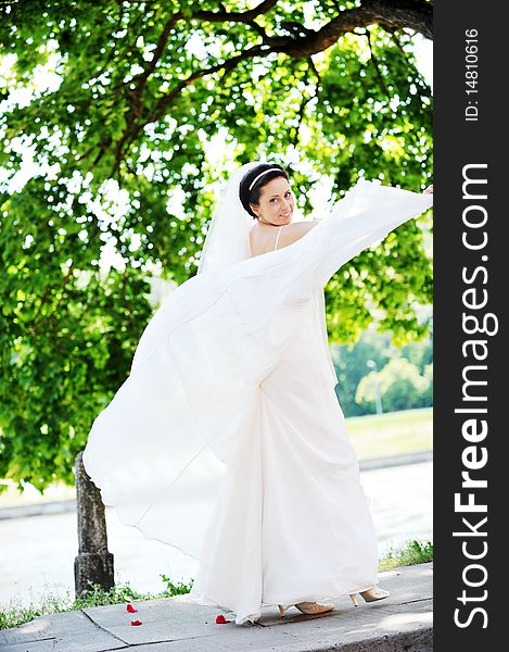 Bride in white dress on background of green trees