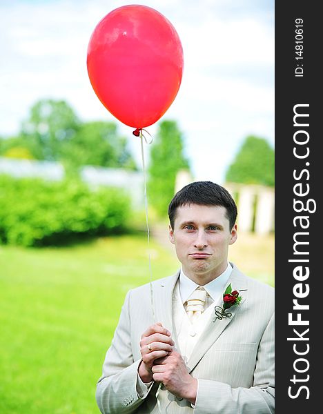 Young groom with balloon on green field. Young groom with balloon on green field