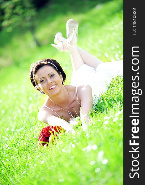 Bride in white dress lying down in  grass.
