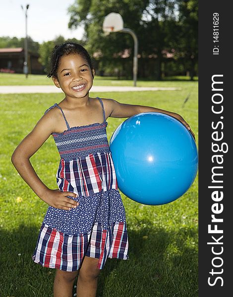 Little girl holding big blue ball at the playground, smiling. Little girl holding big blue ball at the playground, smiling