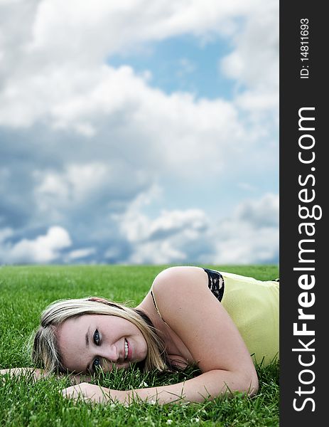 Closeup of a beautiful blond white Caucasian young adult teenage girl laying in a green grass field smiling at the camera. Closeup of a beautiful blond white Caucasian young adult teenage girl laying in a green grass field smiling at the camera.