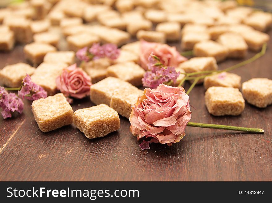 Flower  in the blurred background of cane sugar on a brown wooden table