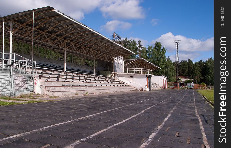 The small stadium with stands and benches for spectators, running tracks are visible with rubber coating