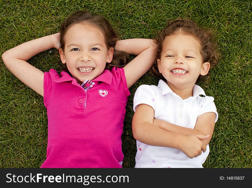 Cute little sisters laying in grass