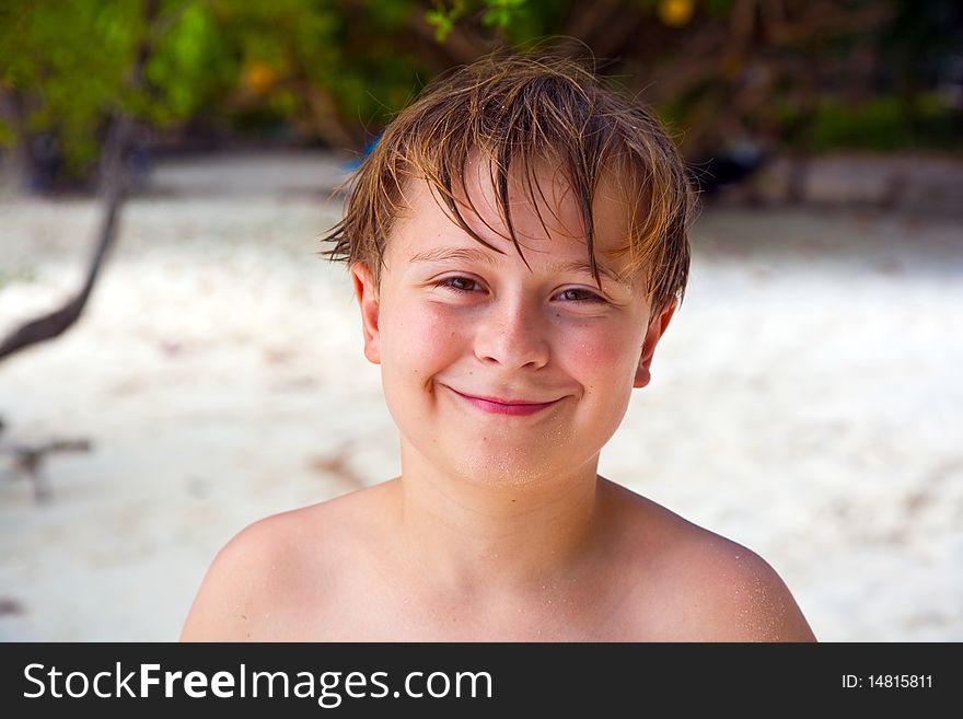 Happy boy with wet hair at the beach smiles and looks very self confident