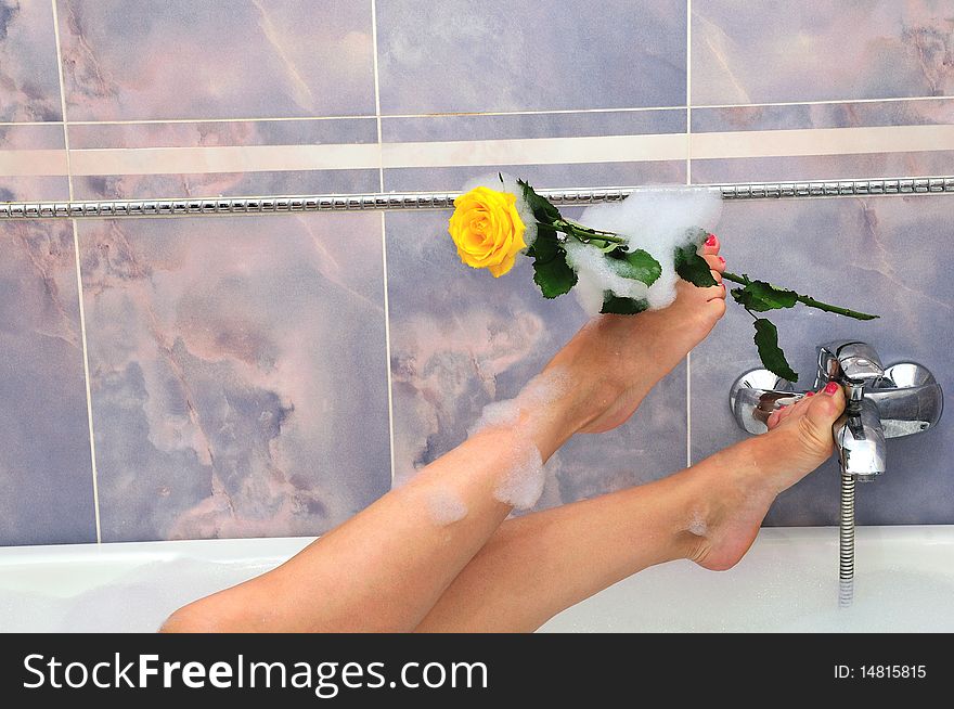 Female's legs with a yellow rose in the bath. Female's legs with a yellow rose in the bath