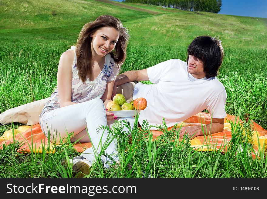 Girl with fruits and boy on grass