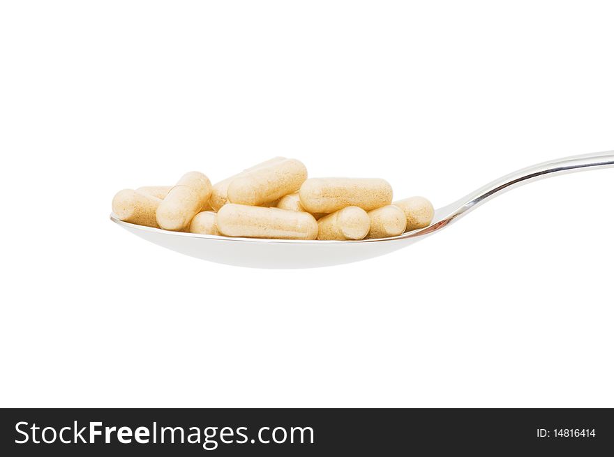 Pills in a spoon isolated on white background