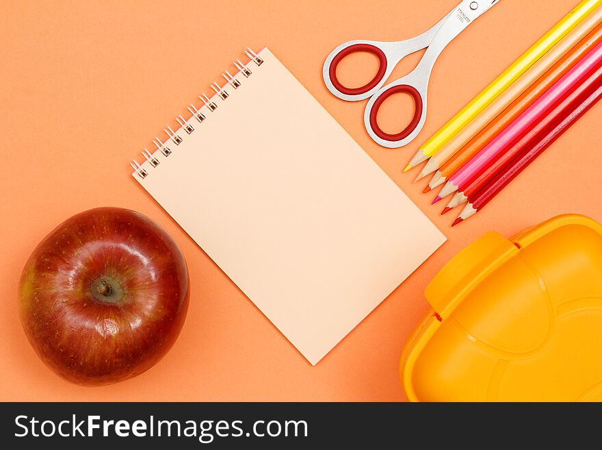 Apple, notebook, scissors, color pencils and lunch box