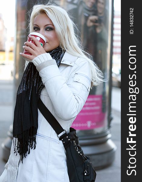 Young blond woman drinks out of a cup