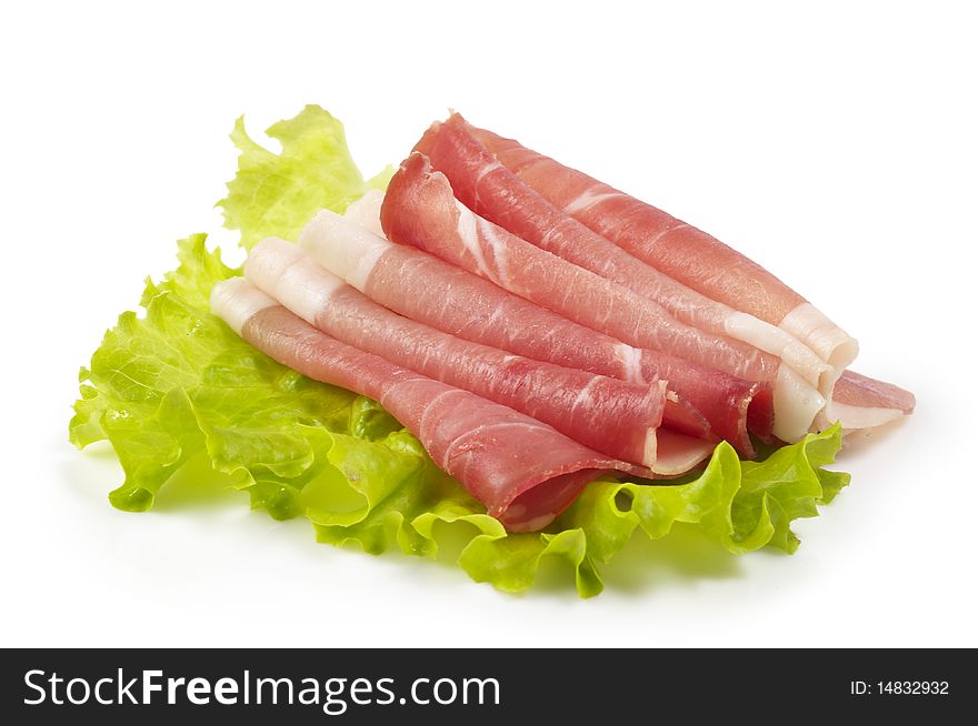 Jamon ham slices isolated over leafs of lettuce macro shot. Jamon ham slices isolated over leafs of lettuce macro shot