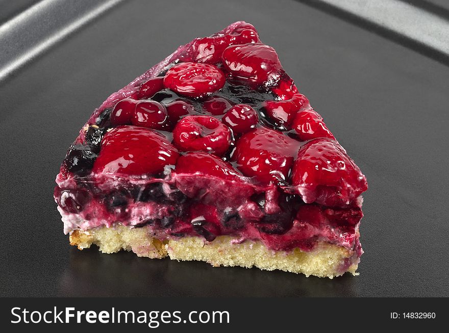 Small berries tart piece macro shot over black background