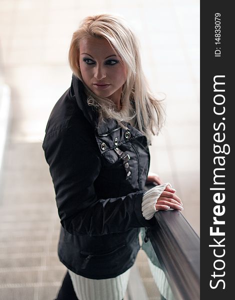 Young blond woman stands on an escalator. Young blond woman stands on an escalator