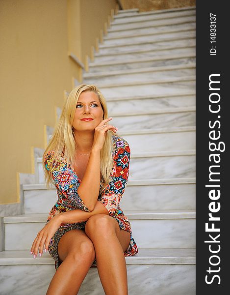 Young beautiful summer woman sitting on the hotel stairs outdoors. Young beautiful summer woman sitting on the hotel stairs outdoors