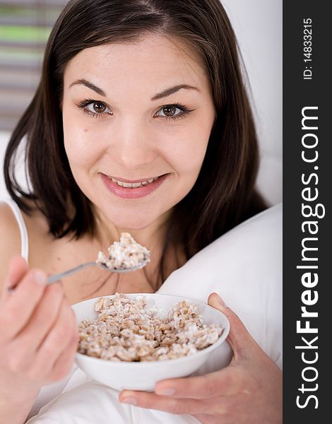 Young adult woman with corn flakes in bed. Young adult woman with corn flakes in bed