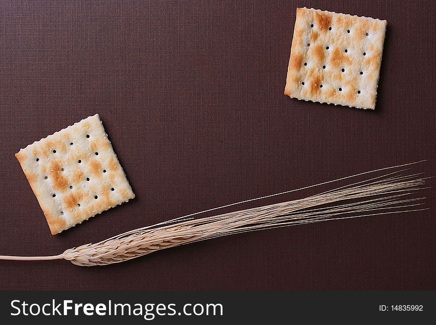 Fresh cookies strewed by salt on a brown background with a dry cone.