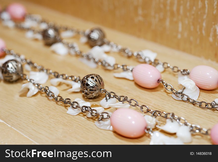 Silver necklace on a wooden surface with large pink and metal beads. Silver necklace on a wooden surface with large pink and metal beads