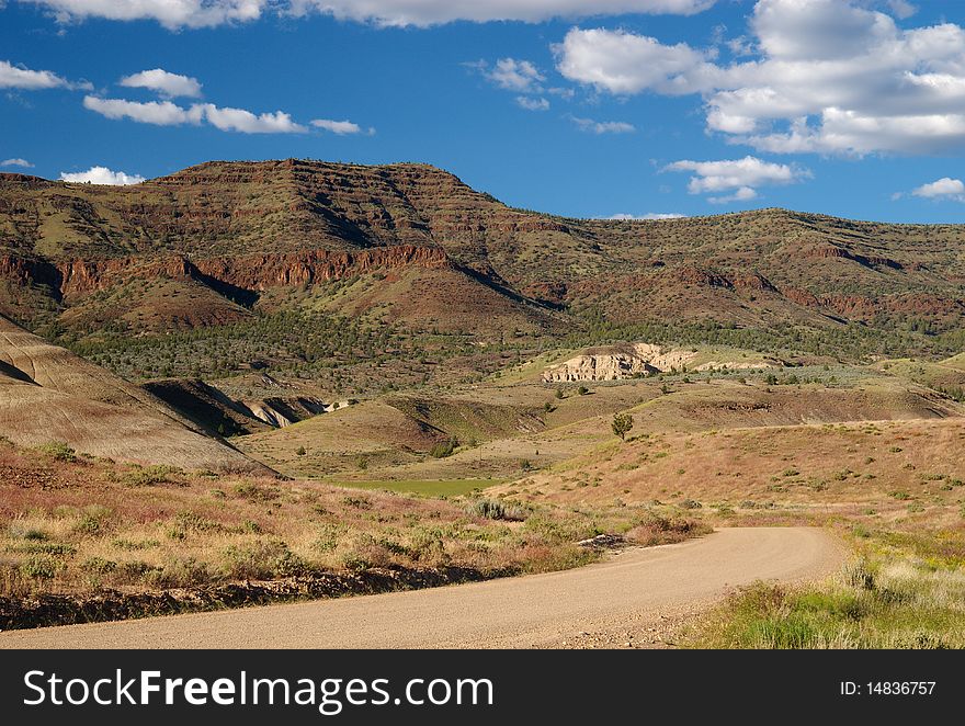 A dirt road winds toward the stark cliffs of the high desert, Mitchell Oregon. A dirt road winds toward the stark cliffs of the high desert, Mitchell Oregon