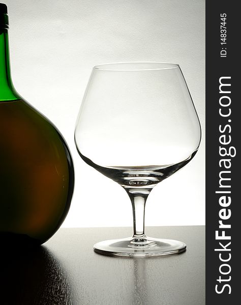 Cognac bottle and glass on grey background