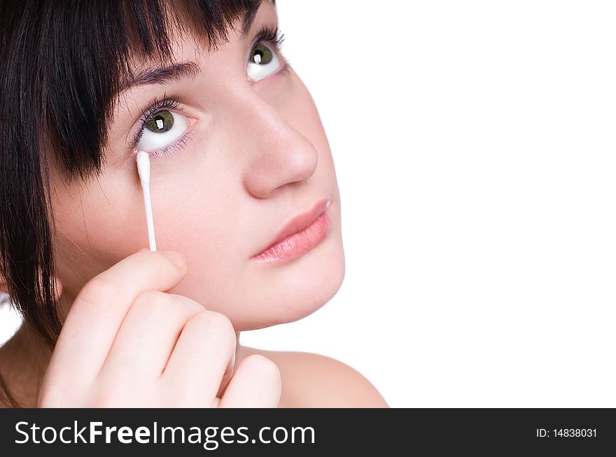 Beautiful young girl removing makeup from eyes with cotton bud isolated on white