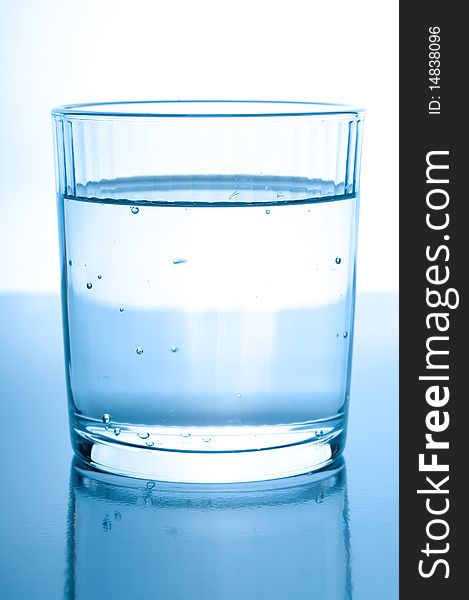 Glass with water on glossy background