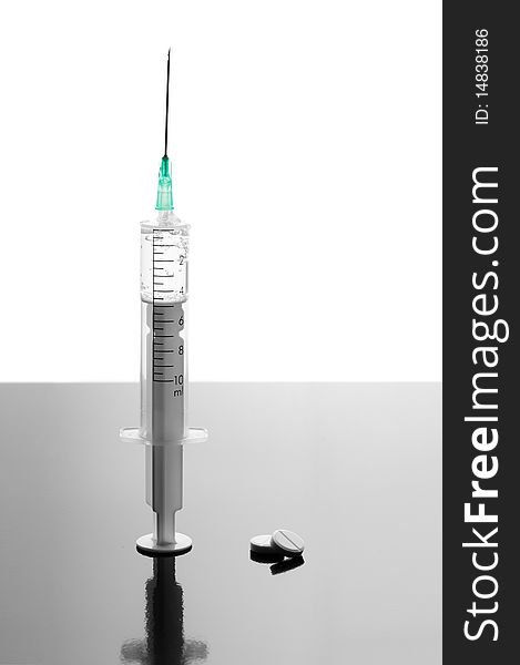 Syringe and tablets on black glossy background