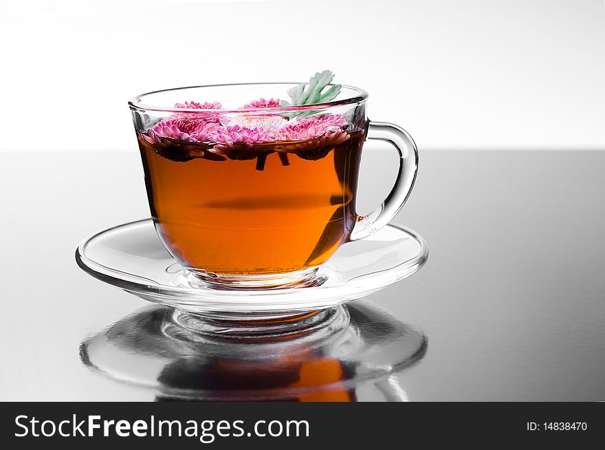 Cup of herbal tea with flowers on glossy background