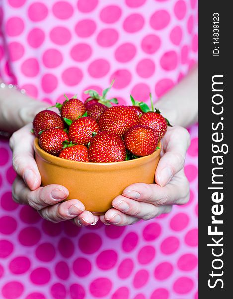 Female hands full of delicious strawberries in bowl