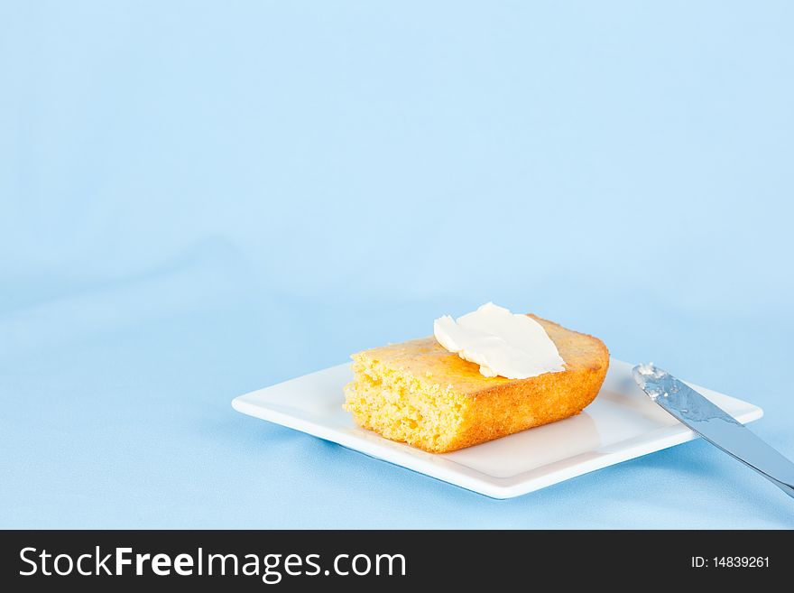 Piece of corn bread with butter on small plate. Piece of corn bread with butter on small plate