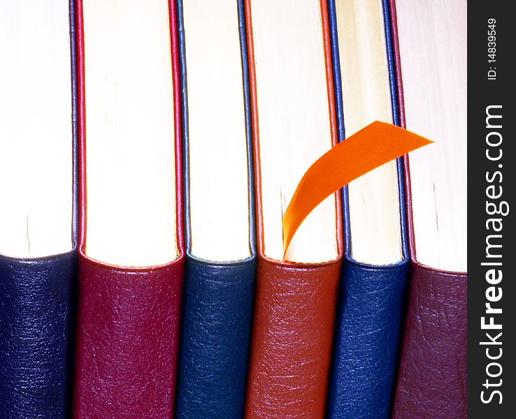 An Orange Bookmark and a Set of Six Leather Bound Books. An Orange Bookmark and a Set of Six Leather Bound Books