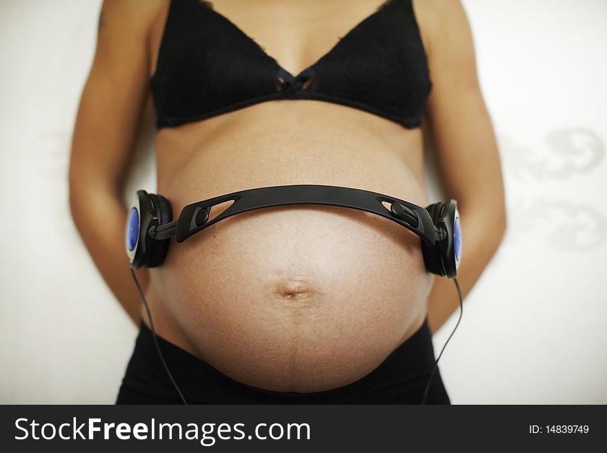 Pregnant woman with headphones on her belly.