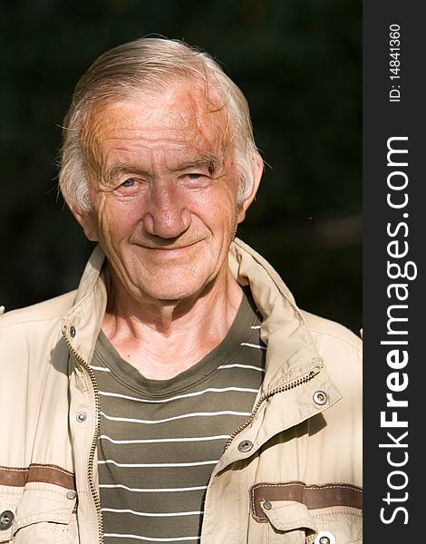 Portrait of the grey-haired elderly man in a beige jacket in village on the nature. Portrait of the grey-haired elderly man in a beige jacket in village on the nature