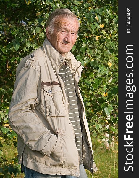 Portrait of the grey-haired elderly man in a beige jacket in village on the nature. Portrait of the grey-haired elderly man in a beige jacket in village on the nature