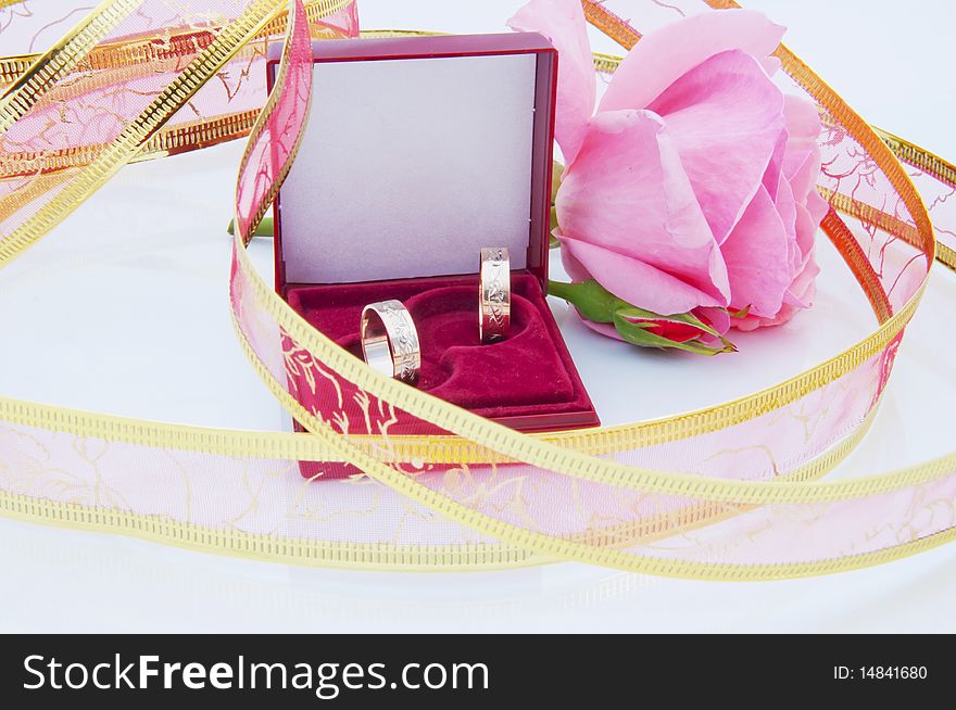 Rose and wedding rings over white