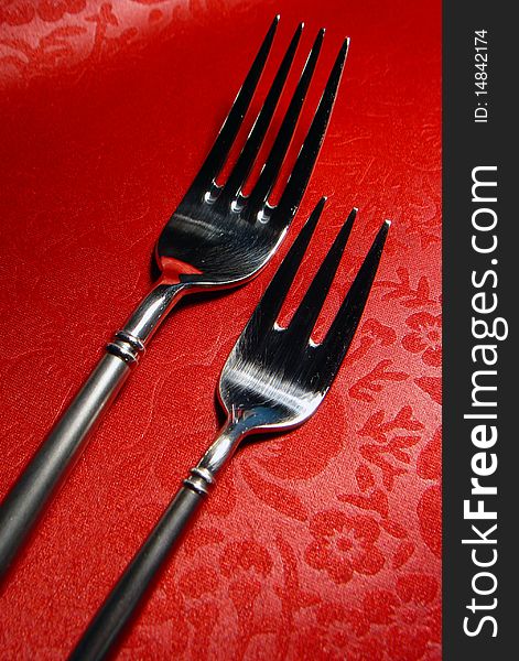 Two forks with red leather background