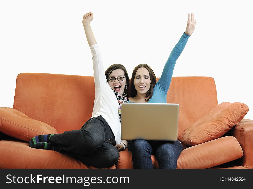 Two happy young woman working on laptop computer on red sofa isolated on white. Two happy young woman working on laptop computer on red sofa isolated on white