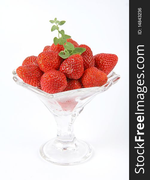 Strawberries in a cup decorated with a lemon balm twig on white background. Strawberries in a cup decorated with a lemon balm twig on white background