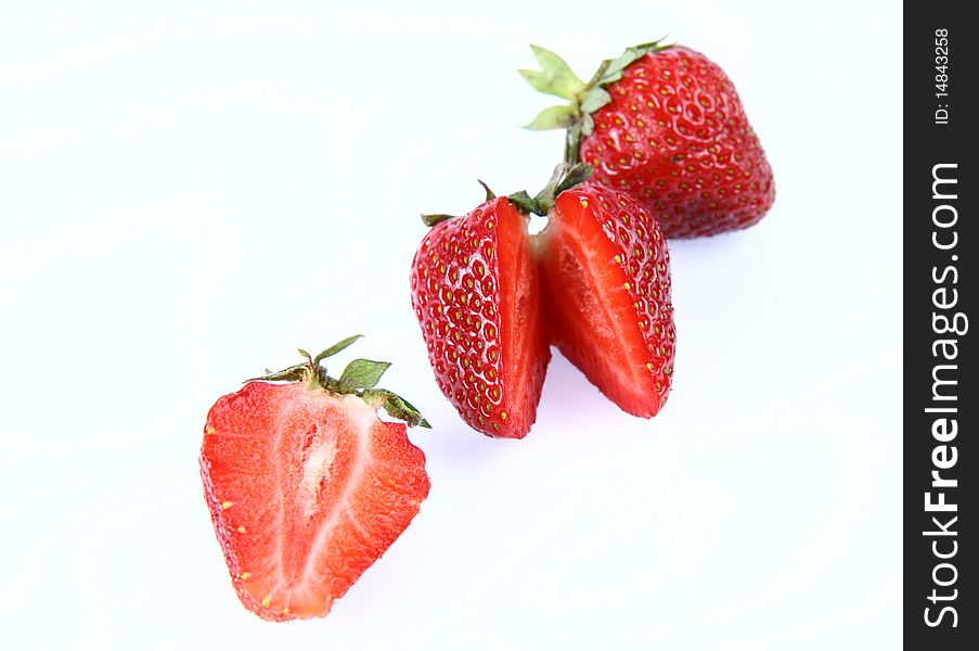 Strawberries on white background (a whole one, a half and one cut in half)