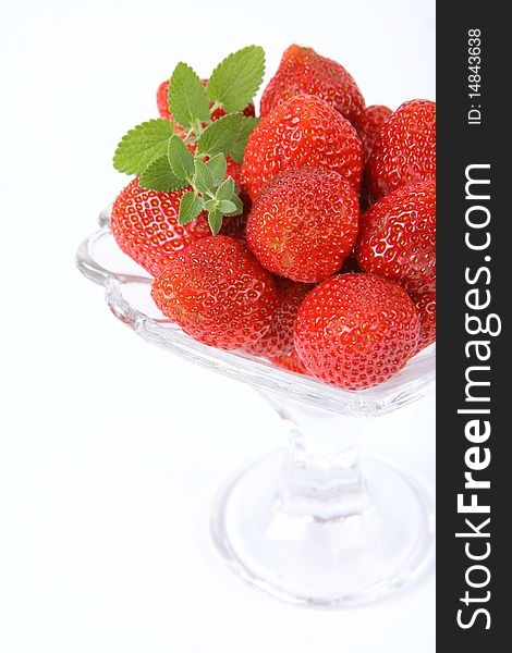 Strawberries in a cup decorated with a lemon balm twig on white background