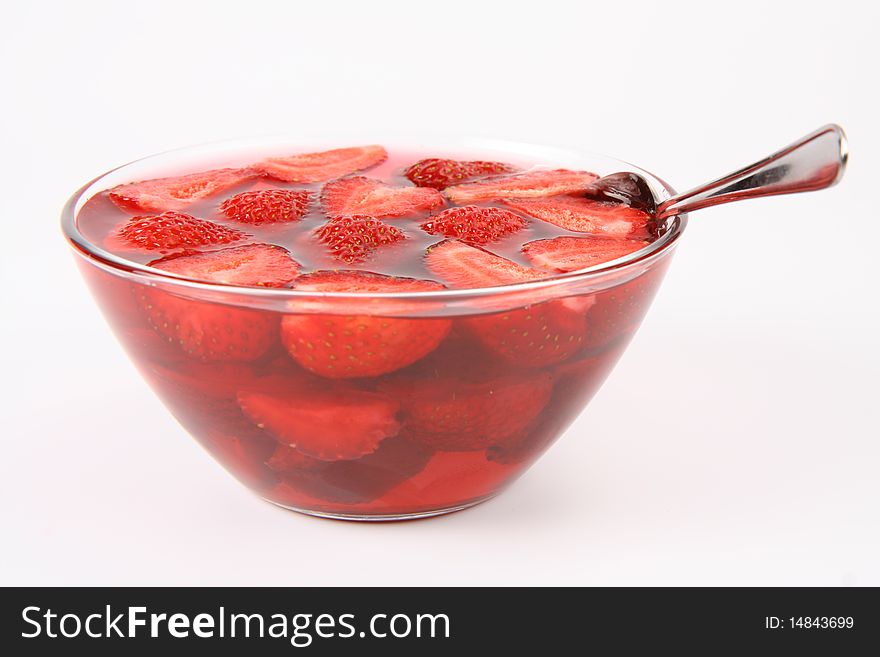 Jelly with strawberries in a bowl and a spoon