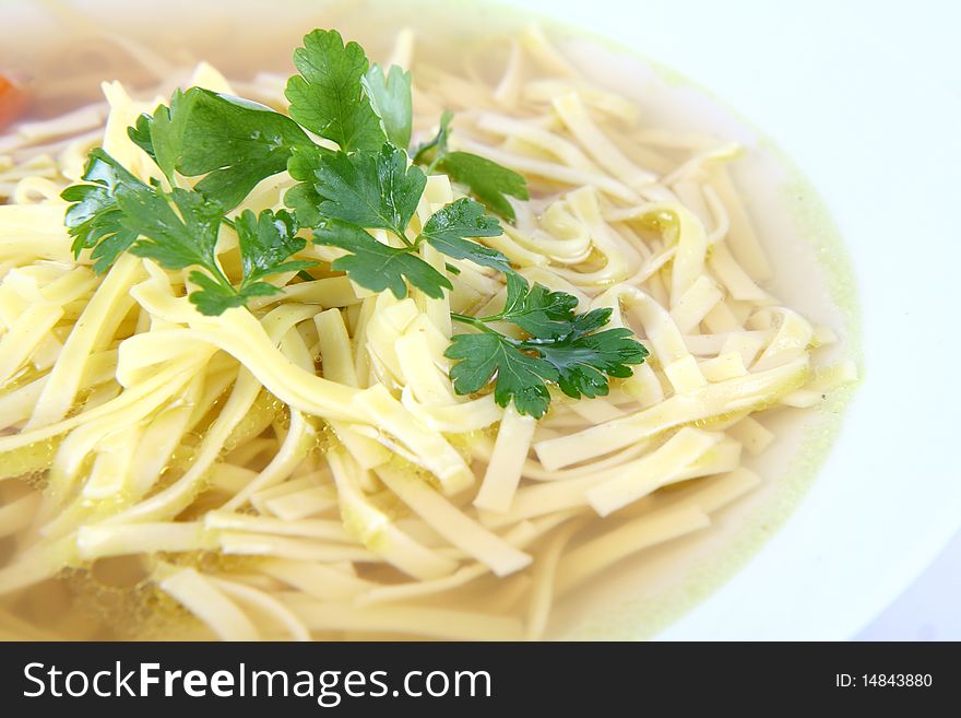 Chicken soup with macaroni decorated with parsley on a plate in close up