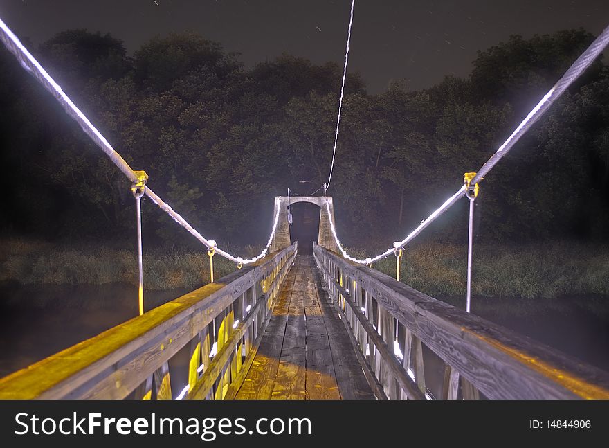 A Bridge with lights leading to a dark forest. A Bridge with lights leading to a dark forest