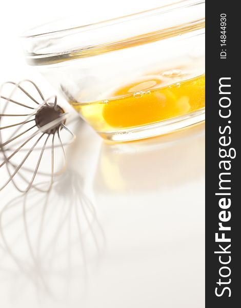 Hand Mixer with Eggs in a Glass Bowl on a Reflective White Background. Hand Mixer with Eggs in a Glass Bowl on a Reflective White Background.