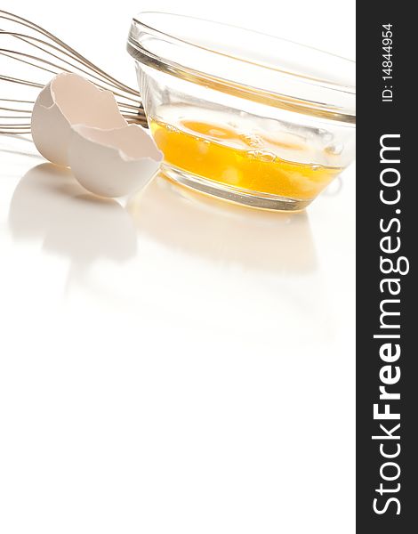 Hand Mixer with Eggs in a Glass Bowl and Shell on a Reflective White Background. Hand Mixer with Eggs in a Glass Bowl and Shell on a Reflective White Background.