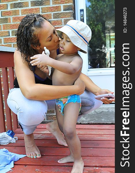 Young boy get a hug and kiss while playing with a toy in hand. Young boy get a hug and kiss while playing with a toy in hand