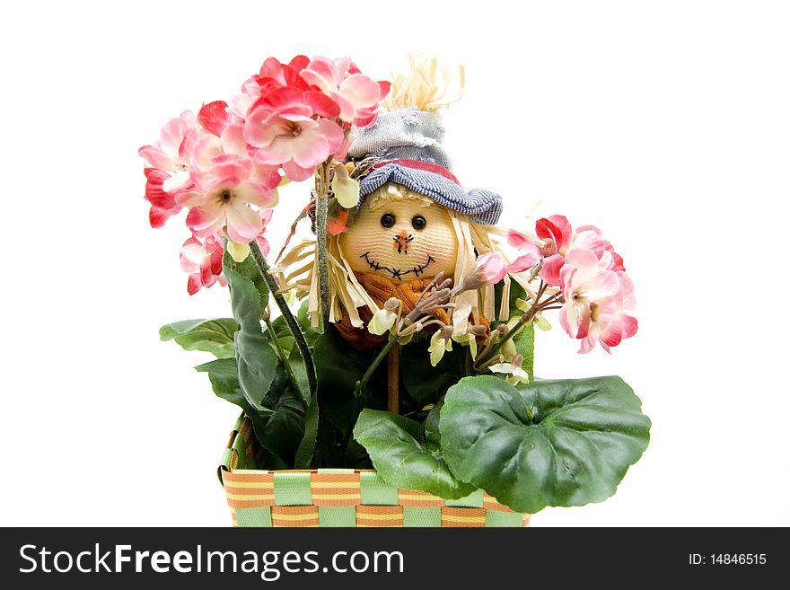 Straw doll behind geranium plant. Straw doll behind geranium plant