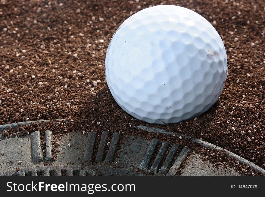 Ball for game in a golf near to a sundial on a ground.