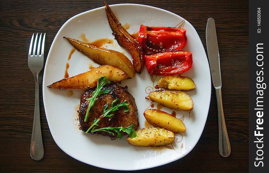 Grilled steak with arugula, served with baked potatoes, paprika and pear. Grilled steak with arugula, served with baked potatoes, paprika and pear